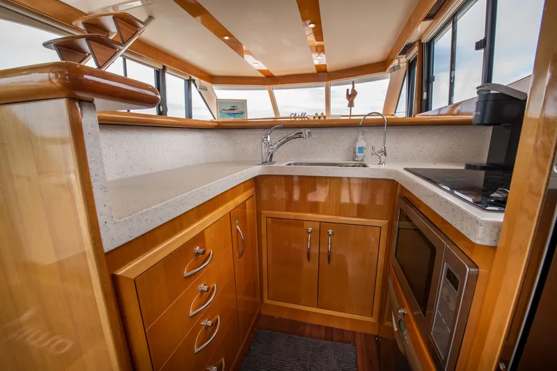 Slide: The Image of 2007 Maritimo Enclosed Fly Bridge kitchen with wooden cabinets and modern appliances. - 43