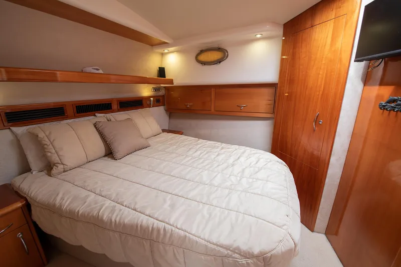Slide: The Image of Luxurious bedroom in 2007 Maritimo Enclosed Fly Bridge yacht with wood accents and cozy bedding. - 46