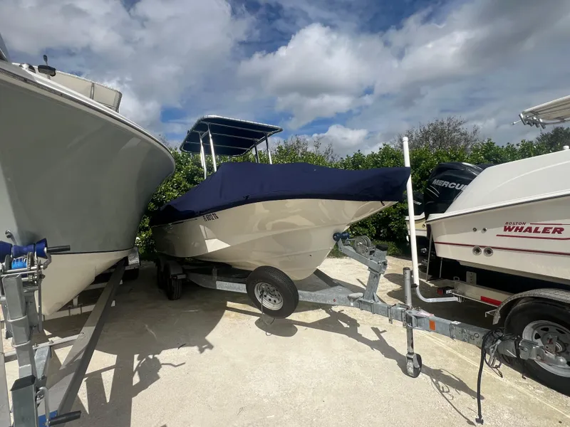 Slide: The Image of 2013 Boston Whaler MONTAUK boat on trailer, covered, parked between two other boats. - 36