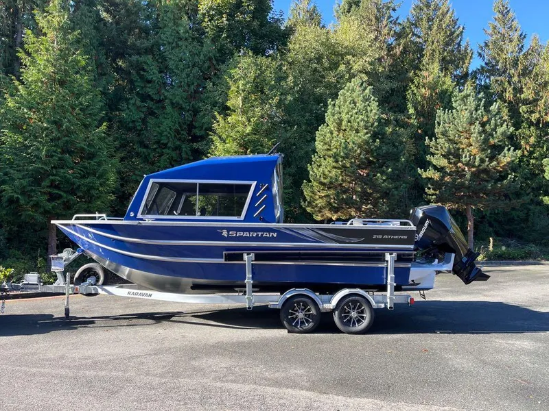 The Image of 2024 Spartan 215 Athens boat on a trailer, parked outdoors with trees in the background. - 0