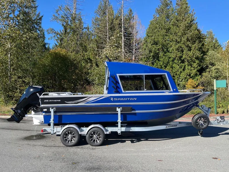 Slide: The Image of 2024 Spartan 215 Athens boat on a trailer, blue exterior, parked outdoors. - 11