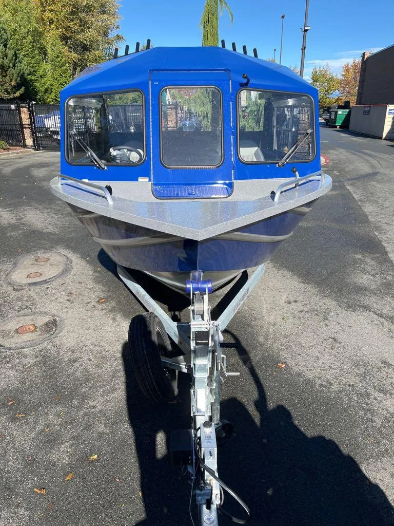 Slide: The Image of 2024 Spartan 215 Athens boat, front view, blue exterior, parked on a trailer. - 13