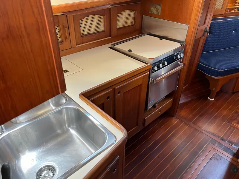 Slide: The Image of Galley kitchen in 1990 Gozzard 36 sailboat with stove, sink, and wooden cabinetry. - 38