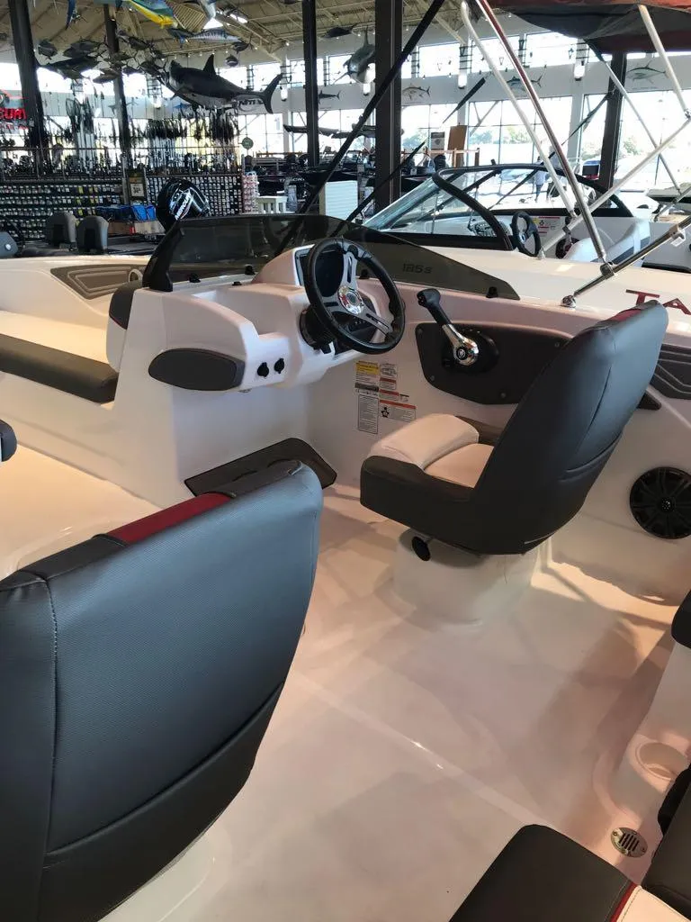 Slide: The Image of 2024 Tahoe T21 boat interior with steering wheel and seating in showroom. - 11