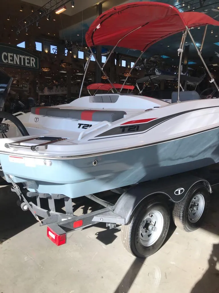 Slide: The Image of 2024 Tahoe T21 boat with red canopy on trailer in showroom. - 2