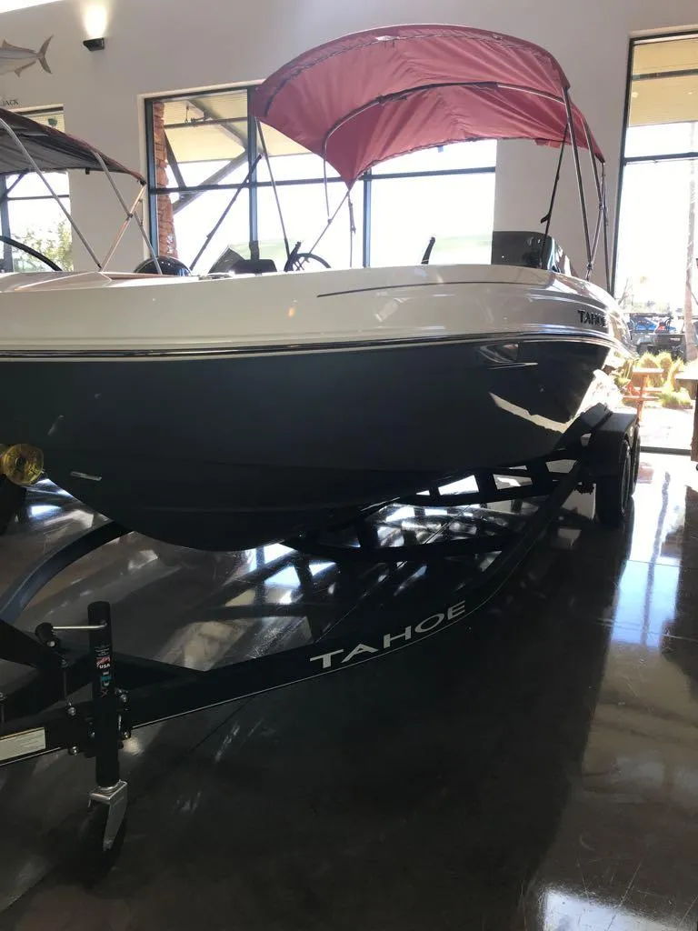 Slide: The Image of 2024 Tahoe T21 boat with red canopy on display indoors. - 3