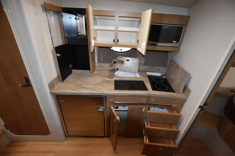 Slide: The Image of 2016 Formula 37 Cruiser kitchen with open cabinets, sink, stove, microwave, and storage drawers. - 26