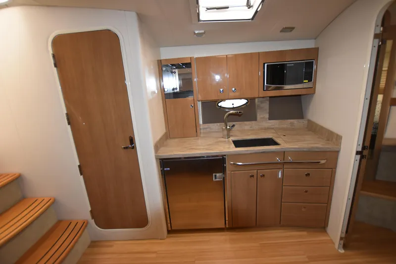 Slide: The Image of 2016 Formula 37 Cruiser kitchen with wooden cabinets, microwave, sink, and stainless steel appliances. - 44