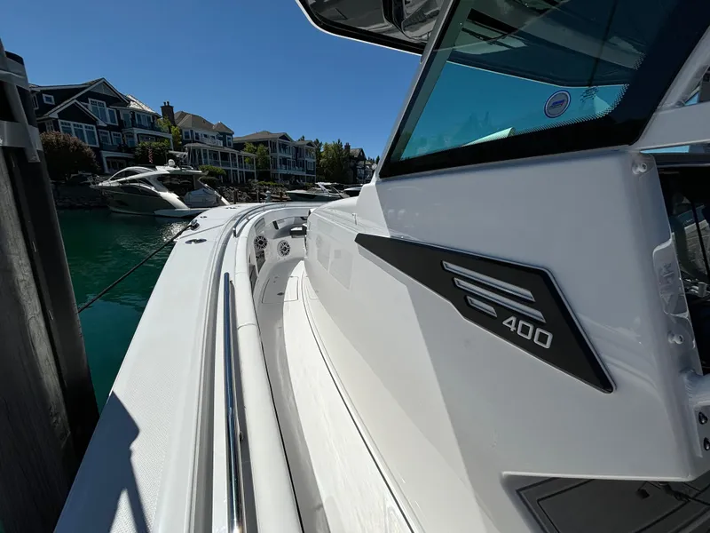 Slide: The Image of 2025 Blackfin 400 CC boat docked in a marina with waterfront homes. - 12