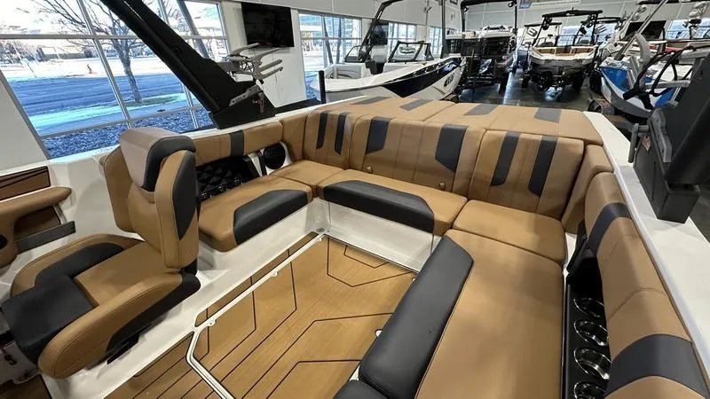 Slide: The Image of 2024 Malibu 21 LX boat interior with tan and black seating in showroom. - 3