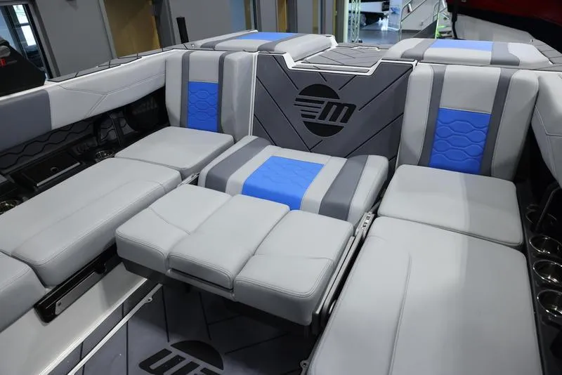 Slide: The Image of 2024 Malibu 23 LSV boat interior with gray and blue cushioned seating. - 23