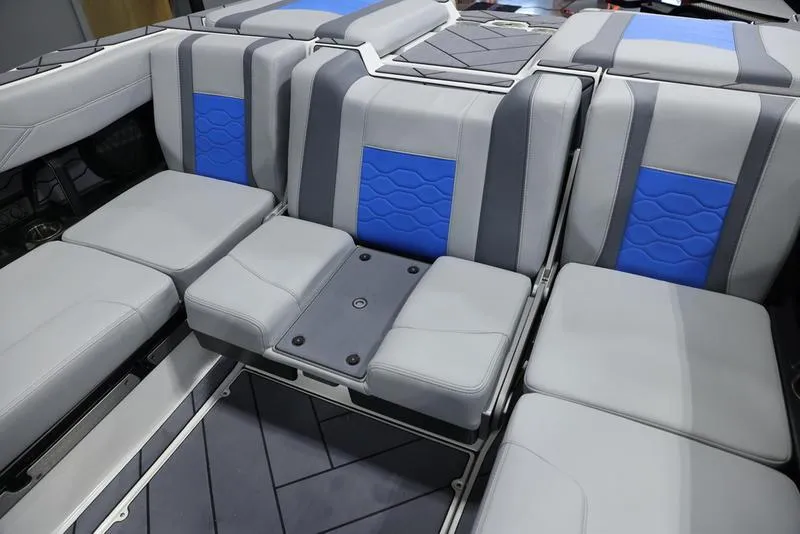 Slide: The Image of 2024 Malibu 23 LSV boat interior with gray and blue cushioned seating. - 24