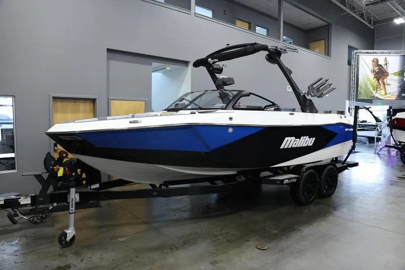 Slide: The Image of 2024 Malibu 23 LSV boat in showroom, blue and black exterior, on trailer. - 4
