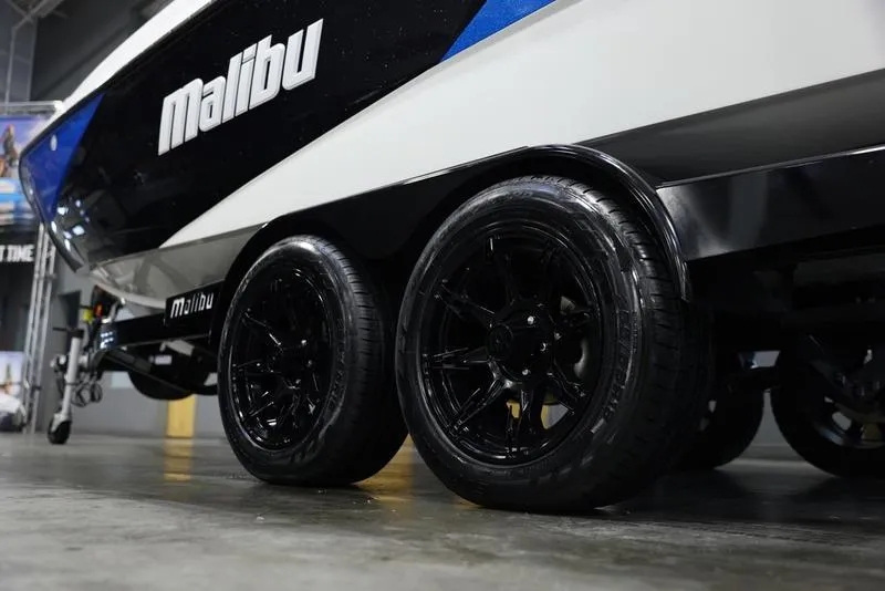 Slide: The Image of 2024 Malibu 23 LSV boat on a trailer with black wheels. - 6