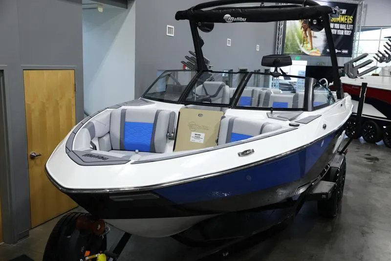 Slide: The Image of 2024 Malibu 23 LSV boat with blue and white interior on display in showroom. - 9