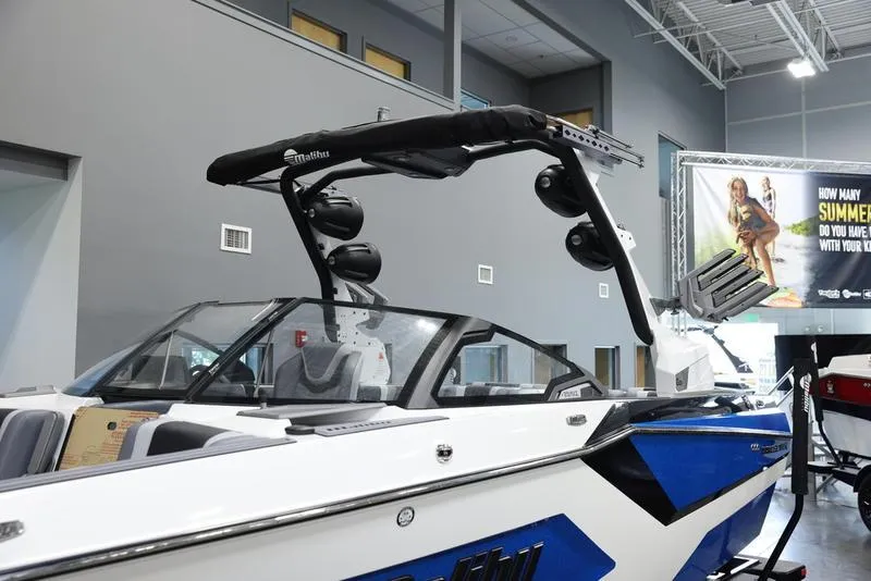 Slide: The Image of 2024 Malibu 23 MXZ boat with blue and white exterior on display indoors. - 13
