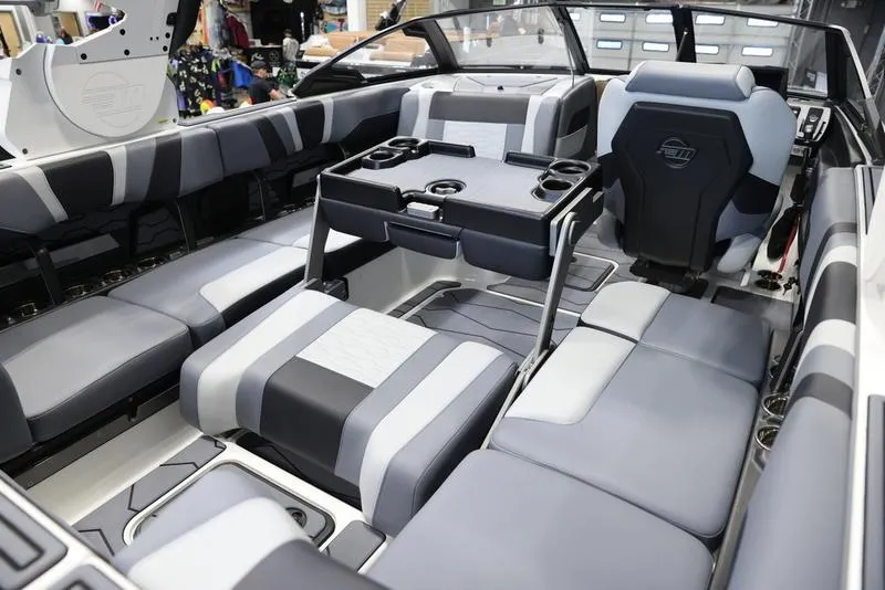 Slide: The Image of 2024 Malibu 23 MXZ boat interior with gray and black seating and a central table. - 26