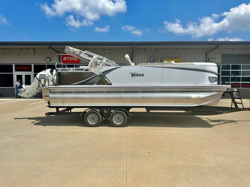 Slide: The Image of 2023 Tahoe Pontoon LTZ Rear Fish boat on a trailer, parked outside a building. - 1