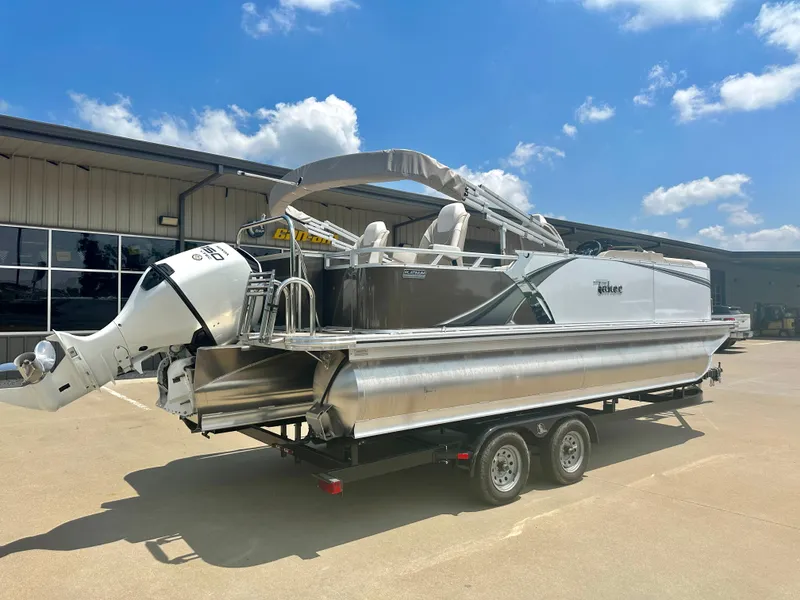 Slide: The Image of 2023 Tahoe Pontoon LTZ Rear Fish boat on a trailer under a clear blue sky. - 2