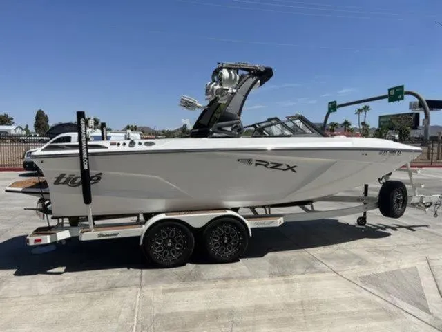 Slide: The Image of 2019 Tigé RZX2 boat on trailer, parked outdoors under clear blue sky. - 36