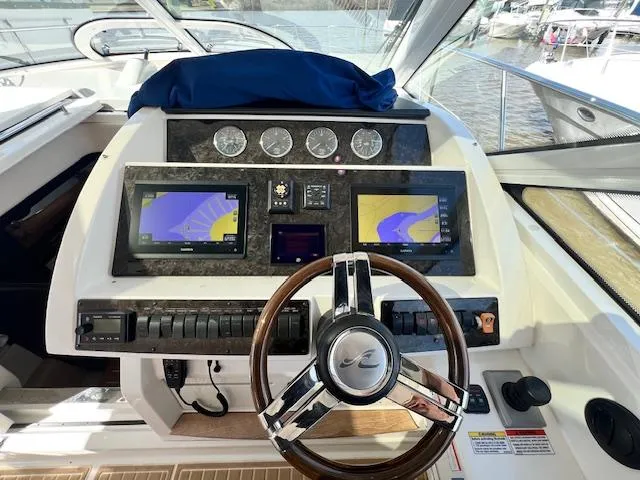 Slide: The Image of Helm of 2010 Sea Ray 450 Sundancer with dual navigation screens and wood-trimmed steering wheel. - 15