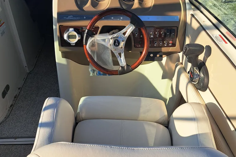 Slide: The Image of 2010 Sea Ray 260 Sun Deck helm with wood-trimmed steering wheel and beige captain's chair. - 9