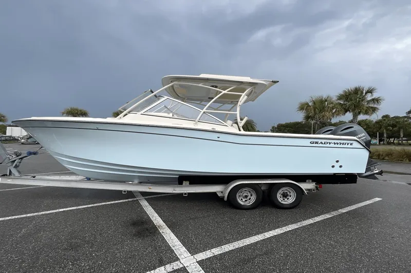 Slide: The Image of 2023 Grady-White Freedom 275 boat on trailer, parked in lot under cloudy sky. - 0