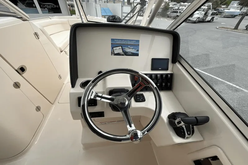 Slide: The Image of 2023 Grady-White Freedom 275 boat helm with steering wheel and controls. - 7