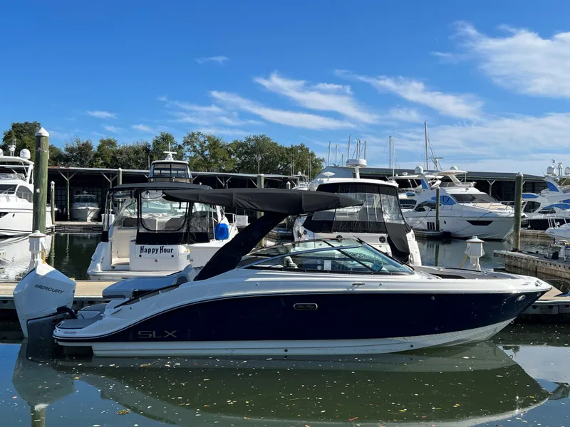 Slide: The Image of 2023 Sea Ray SLX 260 Outboard boat docked in marina under clear blue sky. - 0