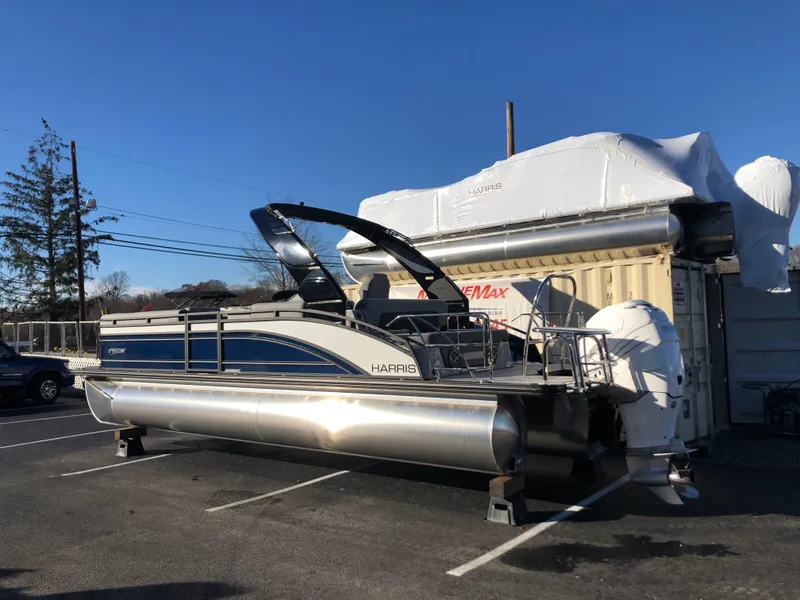 Slide: The Image of 2023 Harris Solstice 250 pontoon boat parked outdoors under clear blue sky. - 1