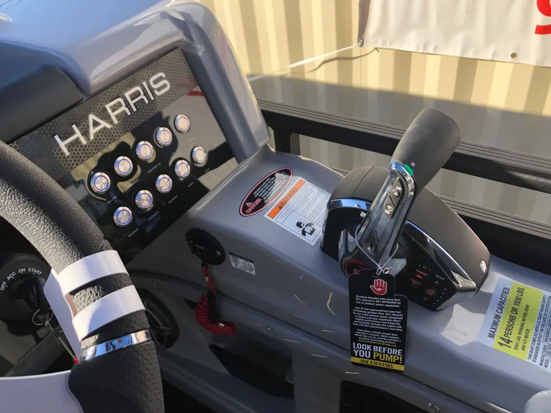 Slide: The Image of 2023 Harris Solstice 250 boat dashboard with controls and warning labels. - 12