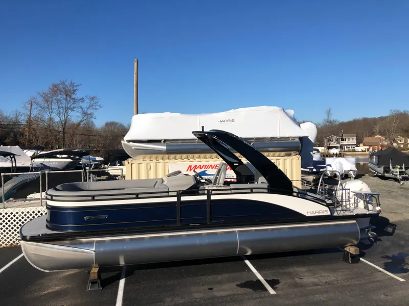 Slide: The Image of 2023 Harris Solstice 250 pontoon boat in a marina parking lot. - 2