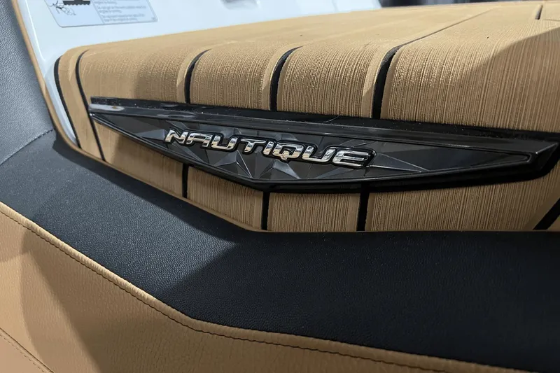 Slide: The Image of 2023 Nautique Super Air Nautique S25 interior detail with logo on tan upholstery. - 24