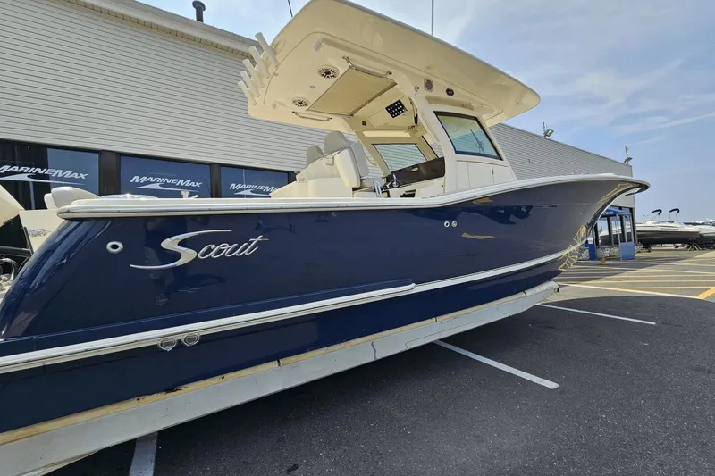Slide: The Image of 2024 Scout 305 LXF boat in a parking lot, blue hull, MarineMax dealership background. - 3