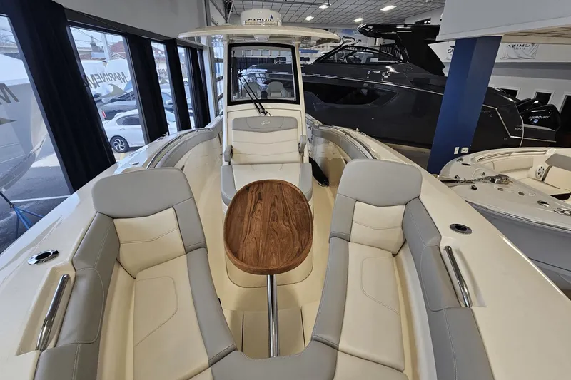 Slide: The Image of 2024 Scout 305 LXF boat interior with seating and wooden table in showroom. - 40