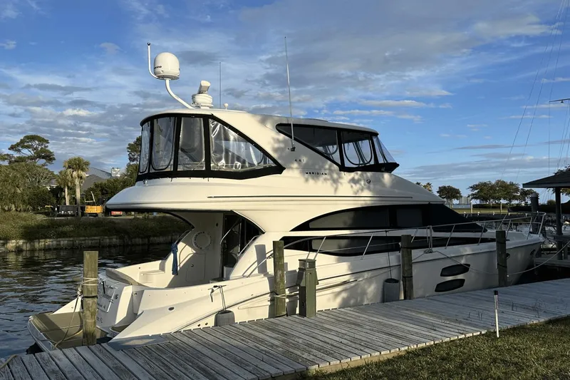 Slide: The Image of 2015 Meridian 441 Sedan yacht docked by a wooden pier under a blue sky. - 2