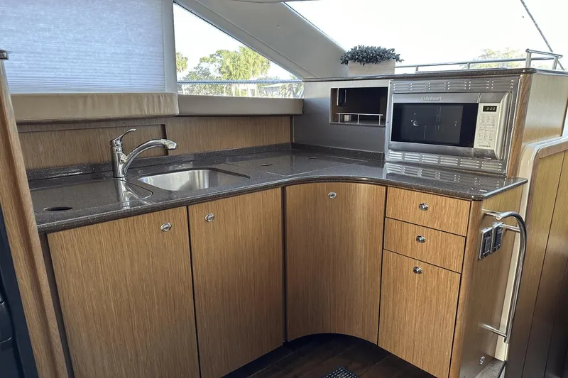 Slide: The Image of 2015 Meridian 441 Sedan yacht kitchen with wood cabinets, sink, and microwave. - 49