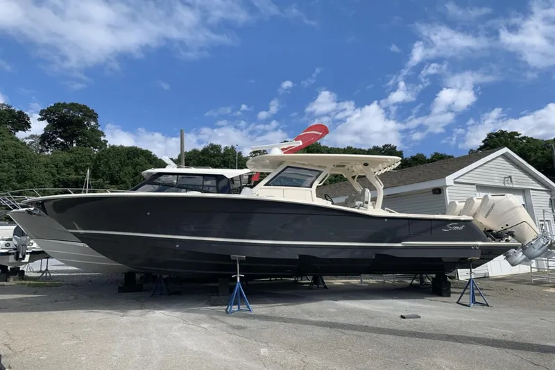 Slide: The Image of 2024 Scout 357LXF boat on stands, outdoors, under a blue sky. - 0