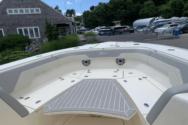 Slide: The Image of 2024 Scout 357LXF boat interior with cushioned seating and sleek design at a marina. - 19