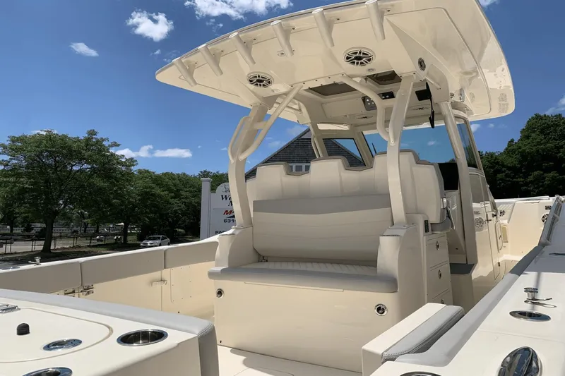 Slide: The Image of 2024 Scout 357LXF boat interior with seating and canopy under clear blue sky. - 9