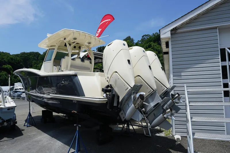 Slide: The Image of 2024 Scout 357LXF boat with triple outboard engines on display outdoors. - 2