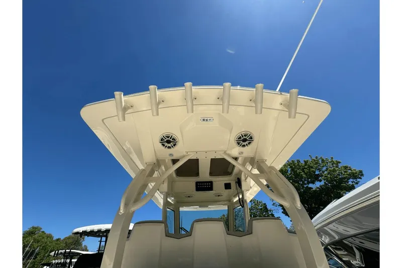 Slide: The Image of 2024 Scout 357LXF boat roof with rod holders and speakers under clear blue sky. - 11