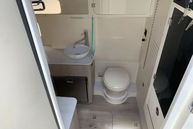 Slide: The Image of 2024 Scout 357LXF boat bathroom with sink, toilet, and storage cabinets. - 23