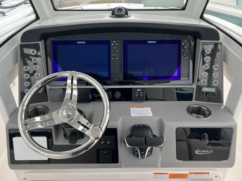 Slide: The Image of 2024 Robalo R270 helm with dual Simrad displays and stainless steel steering wheel. - 8