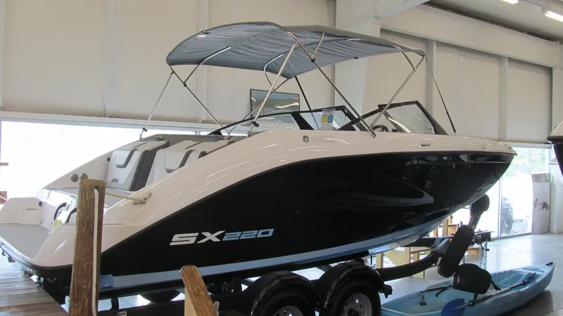 Slide: The Image of 2024 Yamaha Boats SX220 in showroom, sleek design with canopy. - 3