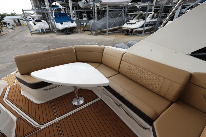 Slide: The Image of 2019 Sea Ray Sundancer 320 interior with tan seating and white table, docked in a marina. - 10