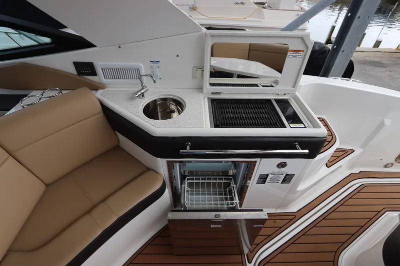 Slide: The Image of 2019 Sea Ray Sundancer 320 yacht interior with kitchenette, featuring sink, grill, and seating area. - 12
