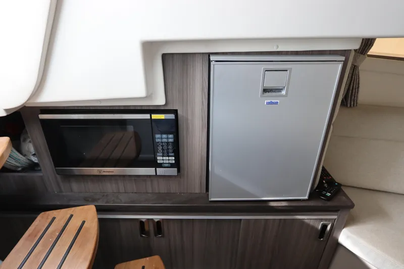 Slide: The Image of 2019 Sea Ray Sundancer 320 interior with microwave and fridge in compact kitchen area. - 37
