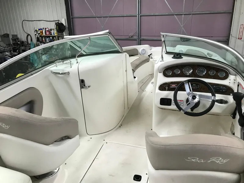 Slide: The Image of 2004 Sea Ray 240 Sundeck interior, featuring helm, seating, and dashboard in a garage. - 11