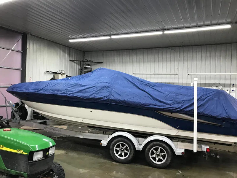 Slide: The Image of 2004 Sea Ray 240 Sundeck boat covered with blue tarp on trailer in garage. - 22